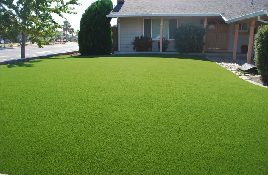 A well-maintained artificial grass lawn in front of a suburban home, providing a clean and low-maintenance outdoor space.