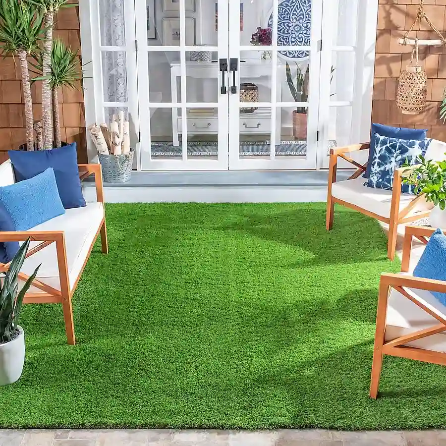 A vibrant green artificial grass rug placed on a patio, surrounded by comfortable seating and potted plants.